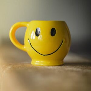 A cheerful yellow ceramic mug with a smiley face design, perfect for adding fun to your kitchenware collection.