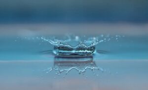 Macro shot of a water droplet creating a ripple effect on the water surface.